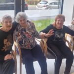 Nasmejane stanovalke sede skupaj in uživajo v druženju po nastopu zunanje skupine.