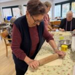 Stanovalka z valjarjem razvaljuje testo za izdelavo slanih okraskov.