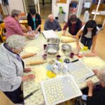 Stanovalci skupaj valjajo in oblikujejo slano testo za ustvarjanje okraskov.