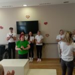 Stanovalka prejme medaljo ob navijanju stanovalk in zaposlenih.