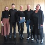 Skupina nastopajočih pozira skupaj na odru po končanem glasbenem programu.