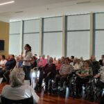 Zbrani stanovalci pozorno spremljajo nastop v dvorani doma.