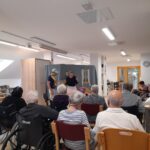 Igralca nastopata pred stanovalci doma med predstavo.