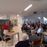 Stanovalci spremljajo komično igrano predstavo v domu.