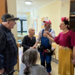 Klovna se v hodniku prijazno pogovarjata s stanovalci in jih spodbujata k smehu.