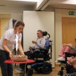 Zaposlena prinese torto z iskrico ob praznovanju rojstnih dni.