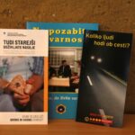 Tri informativne knjižice o varnosti starejših, postavljene pokonci na leseni površini.