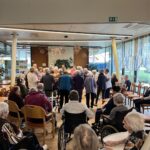 Stanovalci sedijo in opazujejo plese med veselico v domu.