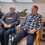 Stanovalca sedita skupaj in spremljata otroški nastop.