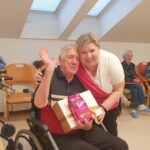 Stanovalec na invalidskem vozičku skupaj z zaposleno pozira s prejeto nagrado božične tombole.