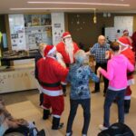 Stanovalci in Božički v avli doma se držijo za roke in plešejo ob božičnem obisku.