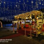 Praznično okrašena božična vas z lesenimi hiškami, darili in toplimi svetlobnimi verigami v večernem času.