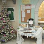 Praznično okrašena avla doma z božičnim drevesom, toplim napitkom in piškoti za obiskovalce.