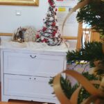 Praznično okrašen kotiček v notranjem prostoru z majhnim božičnim drevescem in zimskimi okraski.