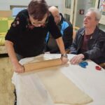 Stanovalka razvalja testo na mizi med pripravo prazničnega peciva.