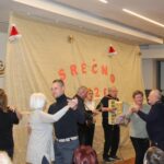 Stanovalci in obiskovalci plešejo ob živi glasbi na praznični prireditvi ob zaključku leta.