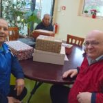 Skupina stanovalcev, zbranih ob praznični mizi, kjer so prejeli darila in skupaj preživeli prijeten popoldan.