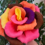 Velika dekorativna roža iz barvnega krep papirja je prikazana od blizu.