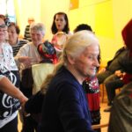 Stanovalci in zaposleni stojijo v krogu ter sodelujejo pri plesu v skupnem prostoru.