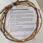 Venec iz trnaste veje leži na listu papirja z natisnjenim besedilom.