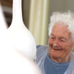 Stanovalka z nasmehom opazuje svoje delo – buča že dobiva lepo, enotno belo podlago.