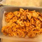 Plastična posoda je napolnjena z ocvrtimi koščki testa različnih oblik.