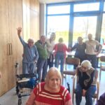 Skupina stanovalcev in zaposlenih stoji skupaj, nasmejani in povezani, kot ob zaključku dogodka ali druženja.