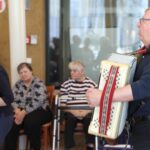 Harmonikar ustvarja prijetno vzdušje, ostali ga spremljajo in uživajo ob glasbi.