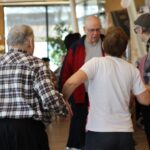 Skupina udeležencev pleše oziroma sodeluje v skupinski aktivnosti – veliko gibanja in druženja.