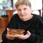 Stanovalka ponosno pokaže svojo dokončano košarico, ki jo je izdelala sama.