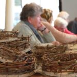 Na mizi so zložene že izdelane košarice, ki kažejo trud, spretnost in ustvarjalnost vseh udeležencev.