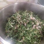 Skleda s sesekljanim zelenjem stoji na mizi.