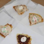 Postreženi vaflji so obloženi z različnimi dodatki, kot so smetana, prelivi in sladkorni okraski.