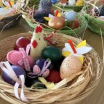 Velikonočne košarice, polne pisanih pirhov in ročnih izdelkov, ustvarjajo praznično in barvito vzdušje.