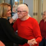 Moški in ženska plešeta v paru, držita se za roke in se nasmejana gibata ob glasbi.