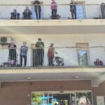 Stanovalci spremljajo prvomajsko budnico z balkonov in pred vhodom doma.