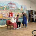 Mladi nastopajoči izvajajo gledališki prizor med predstavo za stanovalce doma za starejše.