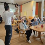 Stanovalci doma za starejše sodelujejo pri glasbenem kvizu z gramofonskimi ploščami.
