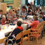 Stanovalci doma za starejše skupaj ustvarjajo cvetlične aranžmaje in okrasne kozarce na ustvarjalni delavnici.