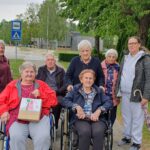 Stanovalci doma za starejše in spremljevalka na skupnem sprehodu ob obisku vrtca.