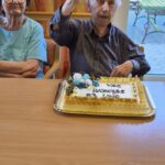 Stanovalec dviga kozarec soka ob rojstnodnevni torti z napisom »Vse najboljše 93 let«.