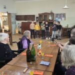 Otroci nastopajo pred stanovalci v jedilnici doma za starejše.