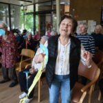 Nasmejana stanovalka doma za starejše uživa v glasbeni in ustvarjalni aktivnosti skupaj z ostalimi udeleženci.