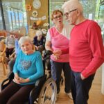 Stanovalec doma za starejše poje ob glasbeni spremljavi med skupinsko pevsko dejavnostjo.
