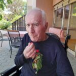 Stanovalec na terasi drži šopek sveže obranih češenj in eno od njih okuša.