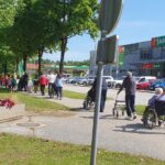 Stanovalci doma starejših, otroci in spremljevalci skupaj hodijo po mestni poti med medgeneracijskim sprehodom in druženjem.
