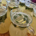 Stekleni vrči z limonado, limono in meto.