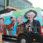 Kombi z reklamo za projekt „Mobilni heroji“ pred stavbo.