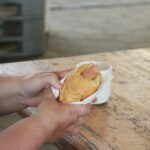 Roke držijo hot dog z gorčico.
