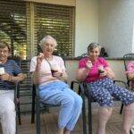 Štiri stanovalke sedijo in pijejo ledeni napitek iz kozarcev.